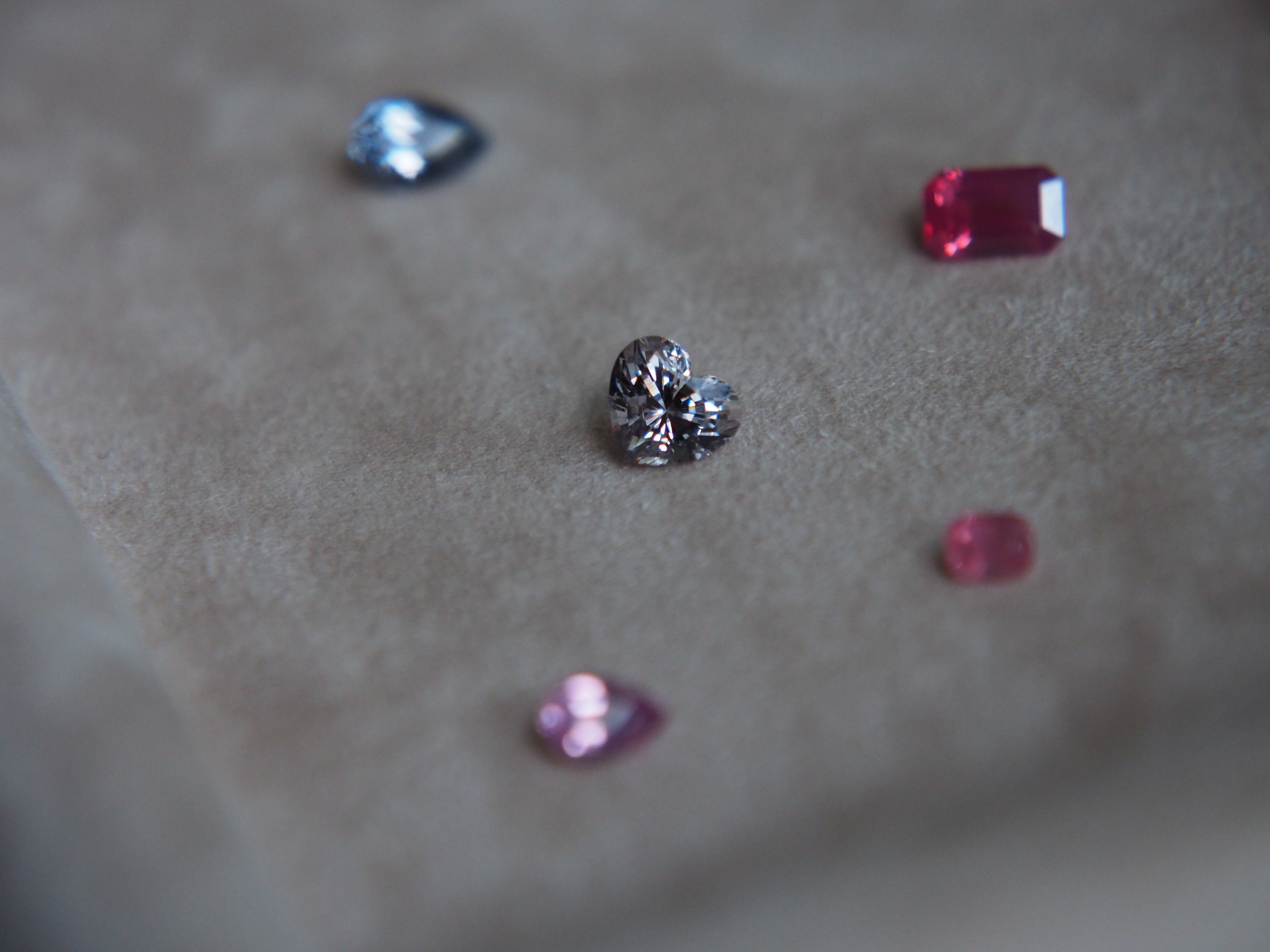 Five different colour spinels placed on top of a velvet beige tray