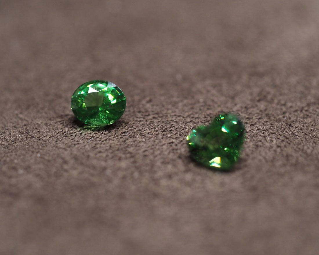 Two tsavorite placed in front of a brown velvet background