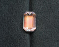 A rainbow moonstone emerald cut sits in front of a green velvet background