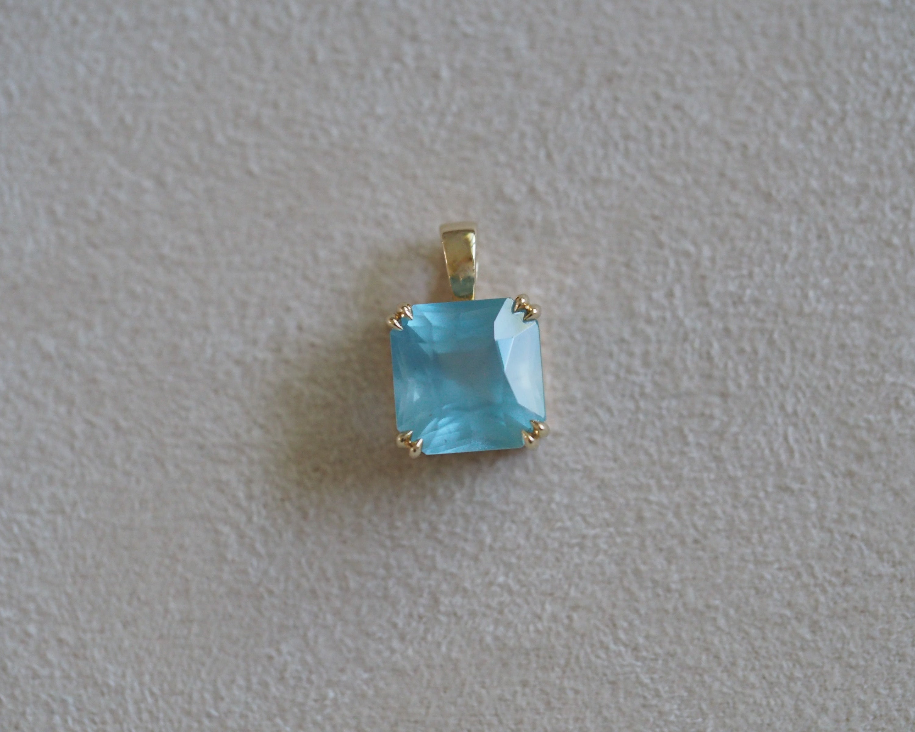 Carolyn Asscher Aquamarine pendant in front of a beige background