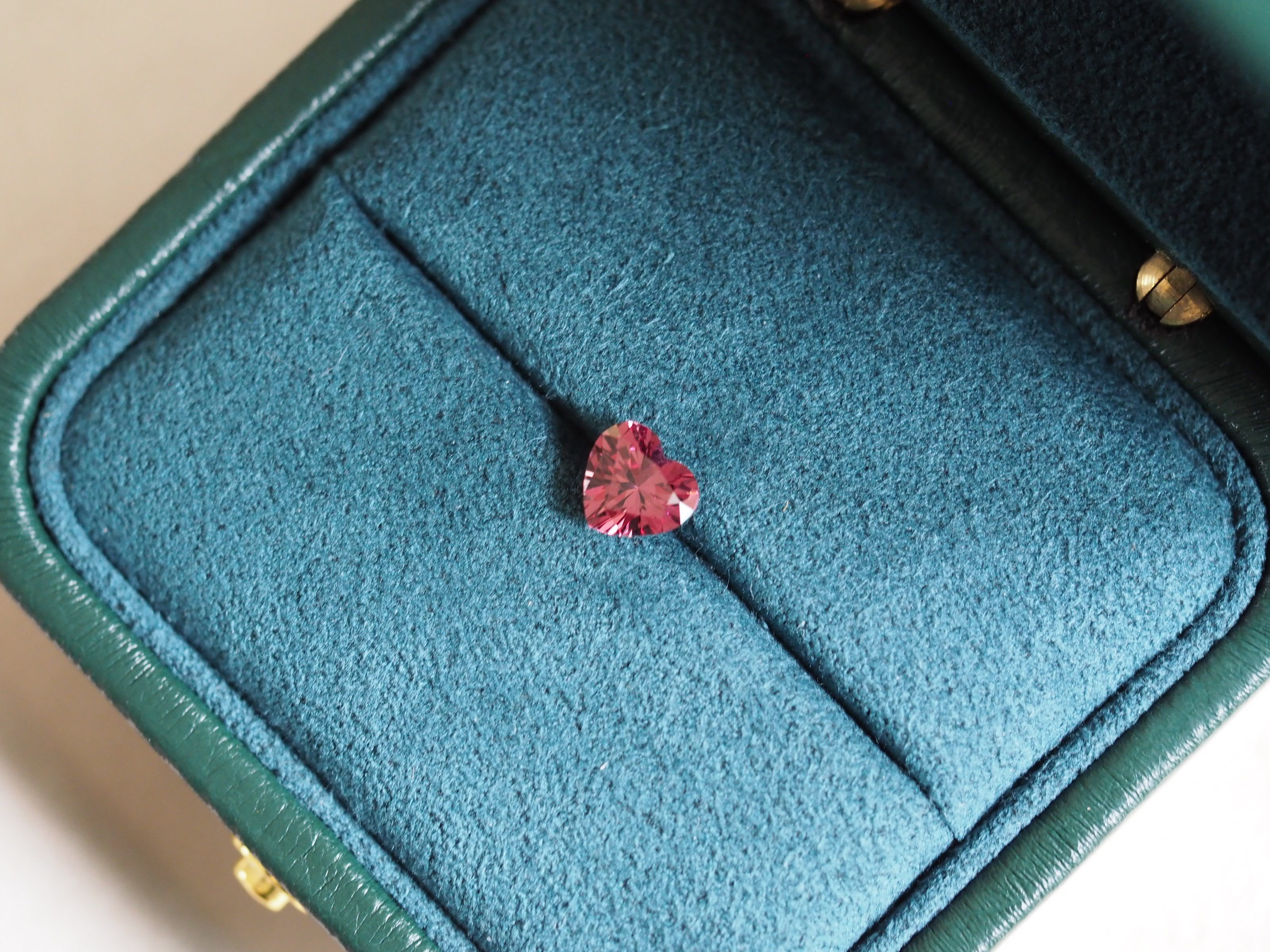 Heart-shaped pink Malaya garnet in a green jewelry box