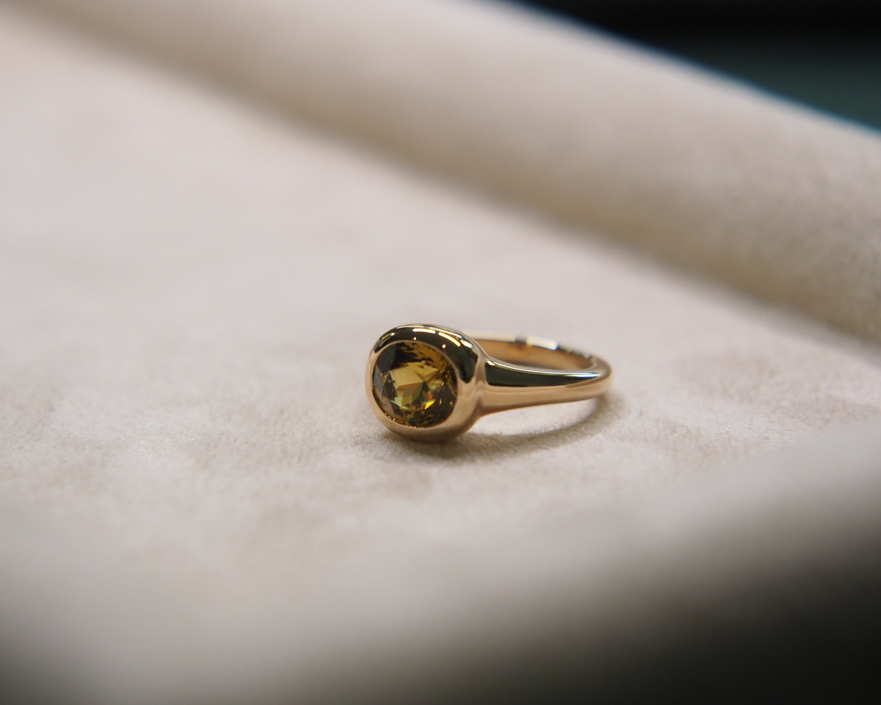 Gold ring with a yellow gemstone on a soft fabric background