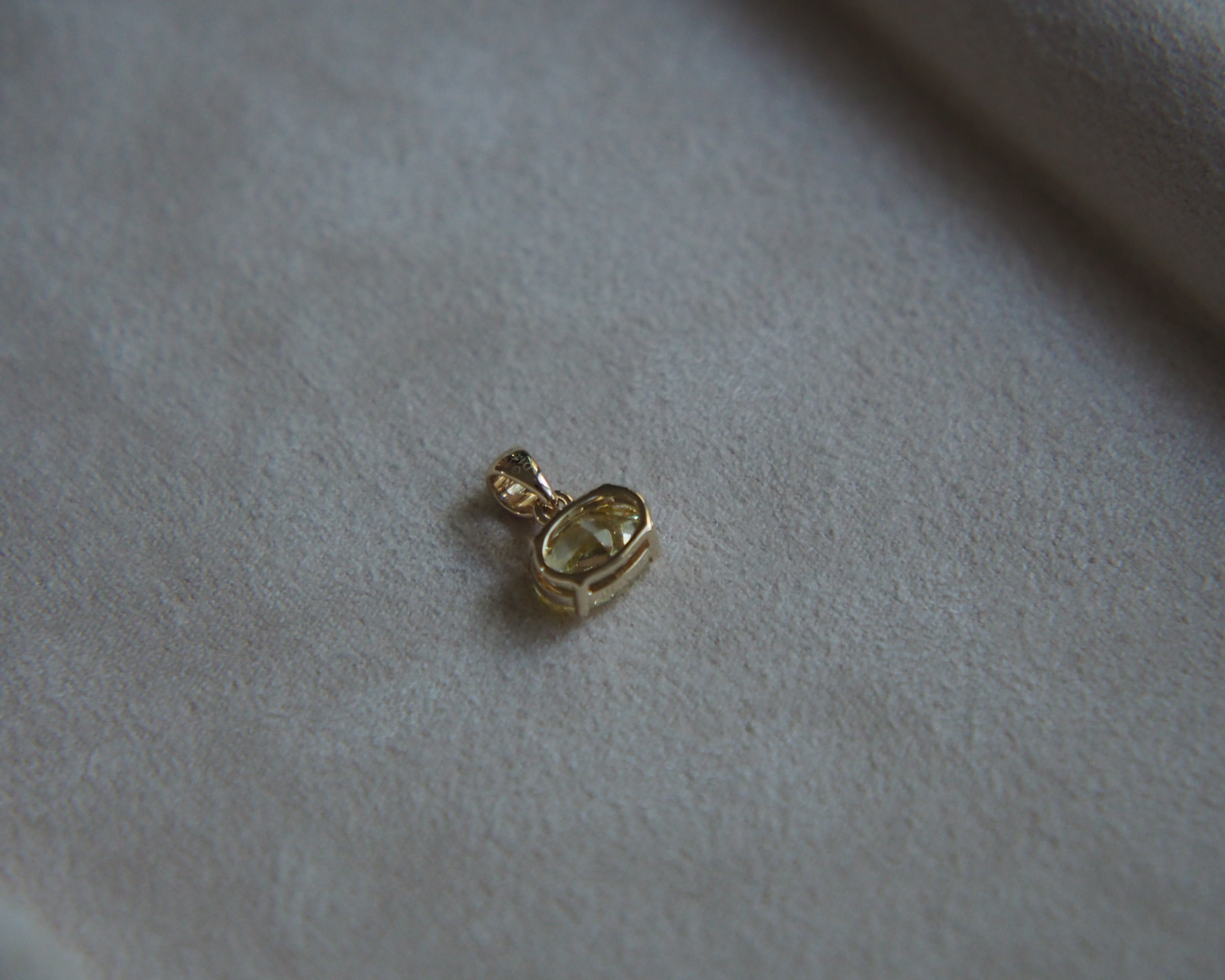 Back of a yellow diamond pendant place on a beige background tray