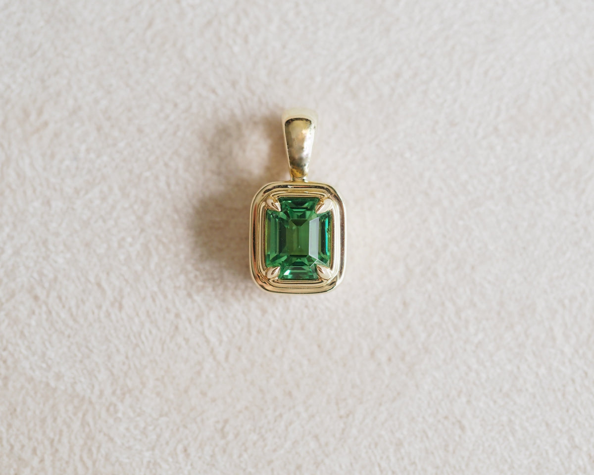 Robyn Natural tsavorite pendant place in front of a beige background.
