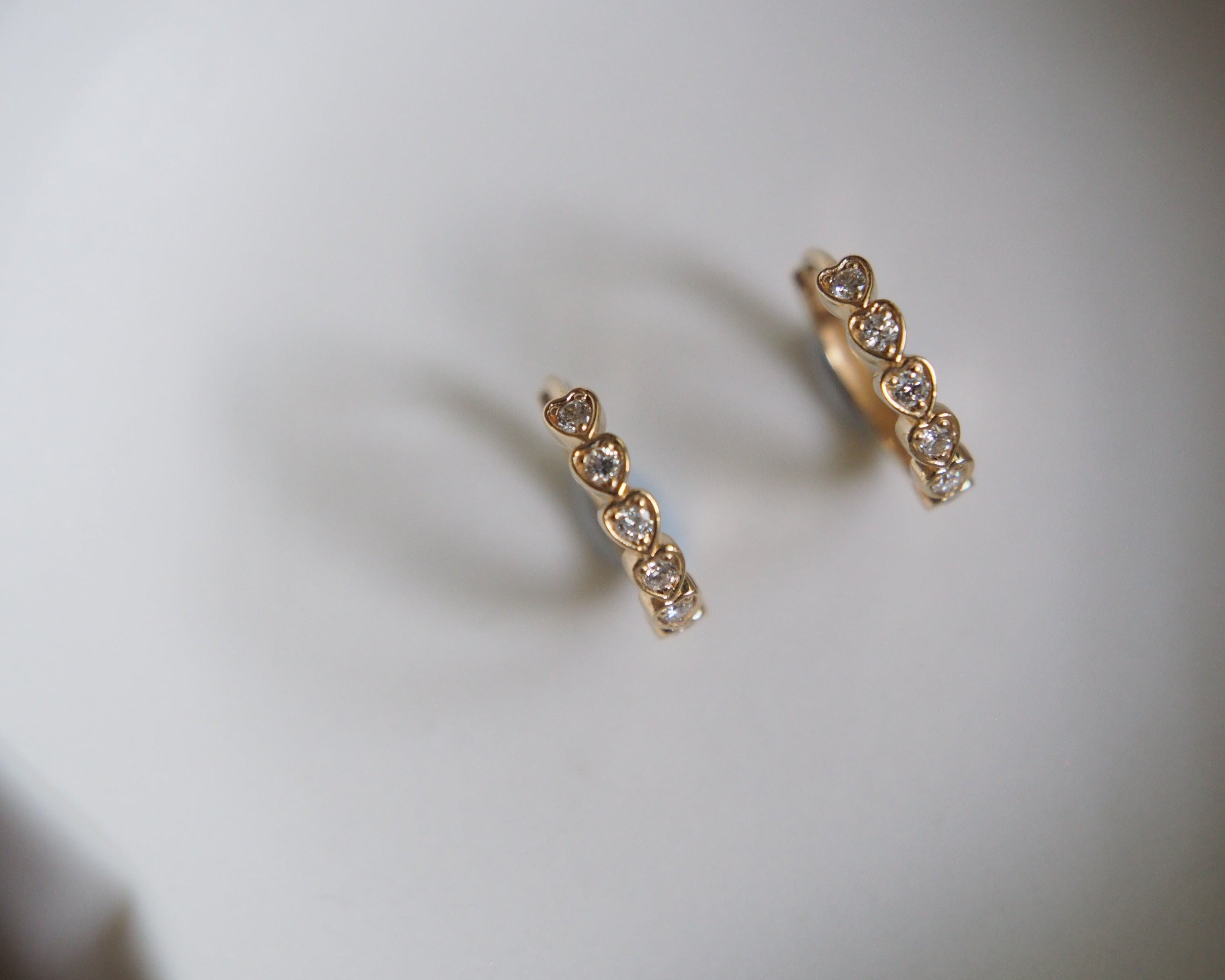 Gold earrings with gemstones on a light gray background
